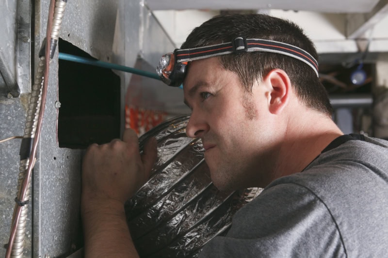 A service tech looking into hVAC unit.